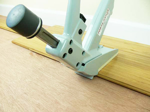 Installing bamboo flooring with secret nail gun onto joists